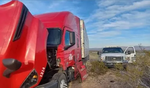 Red semi truck with hood open receiving 24/7 mobile roadside assistance in a desert area near Mohave Valley.
