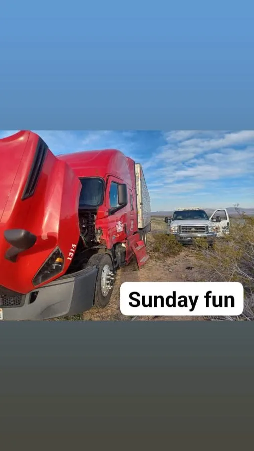 Red semi truck with hood open receiving 24/7 mobile roadside assistance in a desert area near Mohave Valley