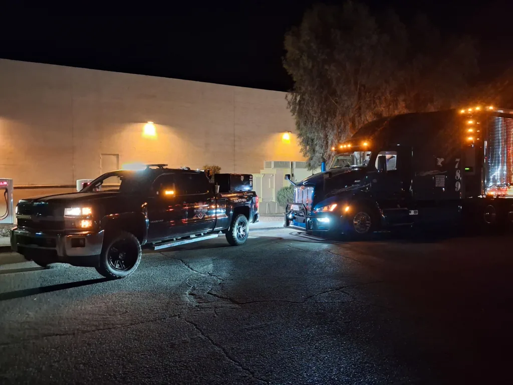 TRT Roadside Service vehicle performing a night diesel repair on a commercial semi-truck along AZ-95.