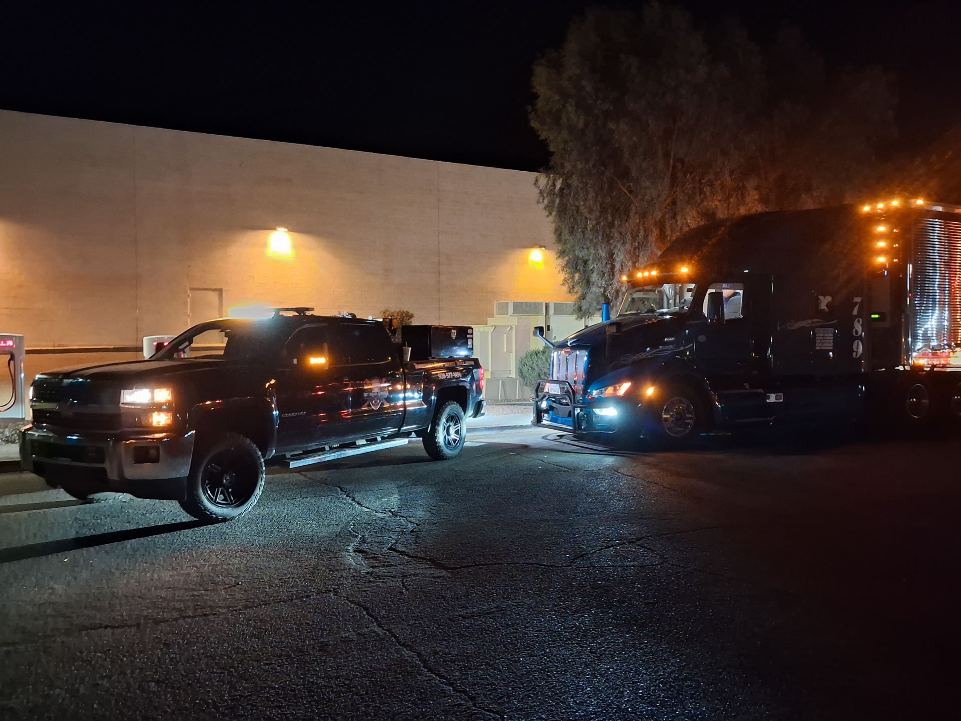TRT Roadside Service vehicle performing a night diesel repair on a commercial semi-truck along AZ-95.